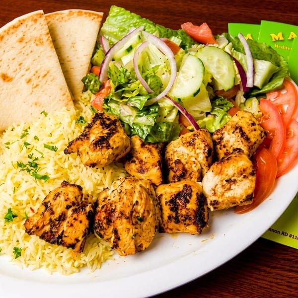 Manna Mediterranean chicken shish kebab plate with rice, salad, pita bread, and a bell pepper.