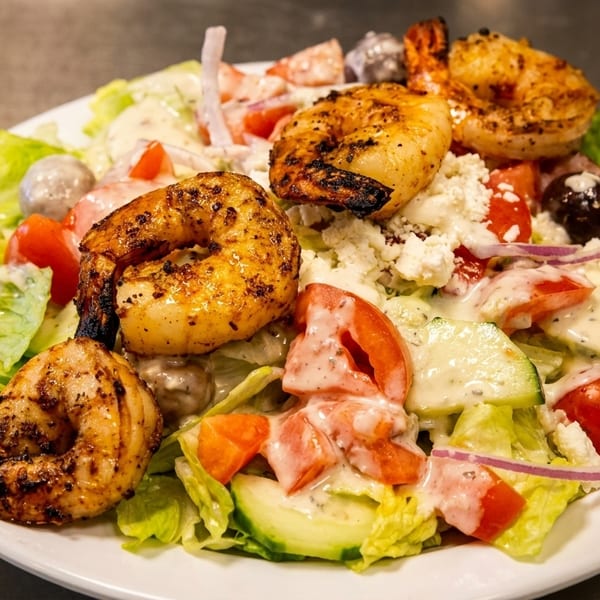Grilled shrimp salad with lettuce, tomatoes, cucumbers, olives, feta, and creamy dressing.